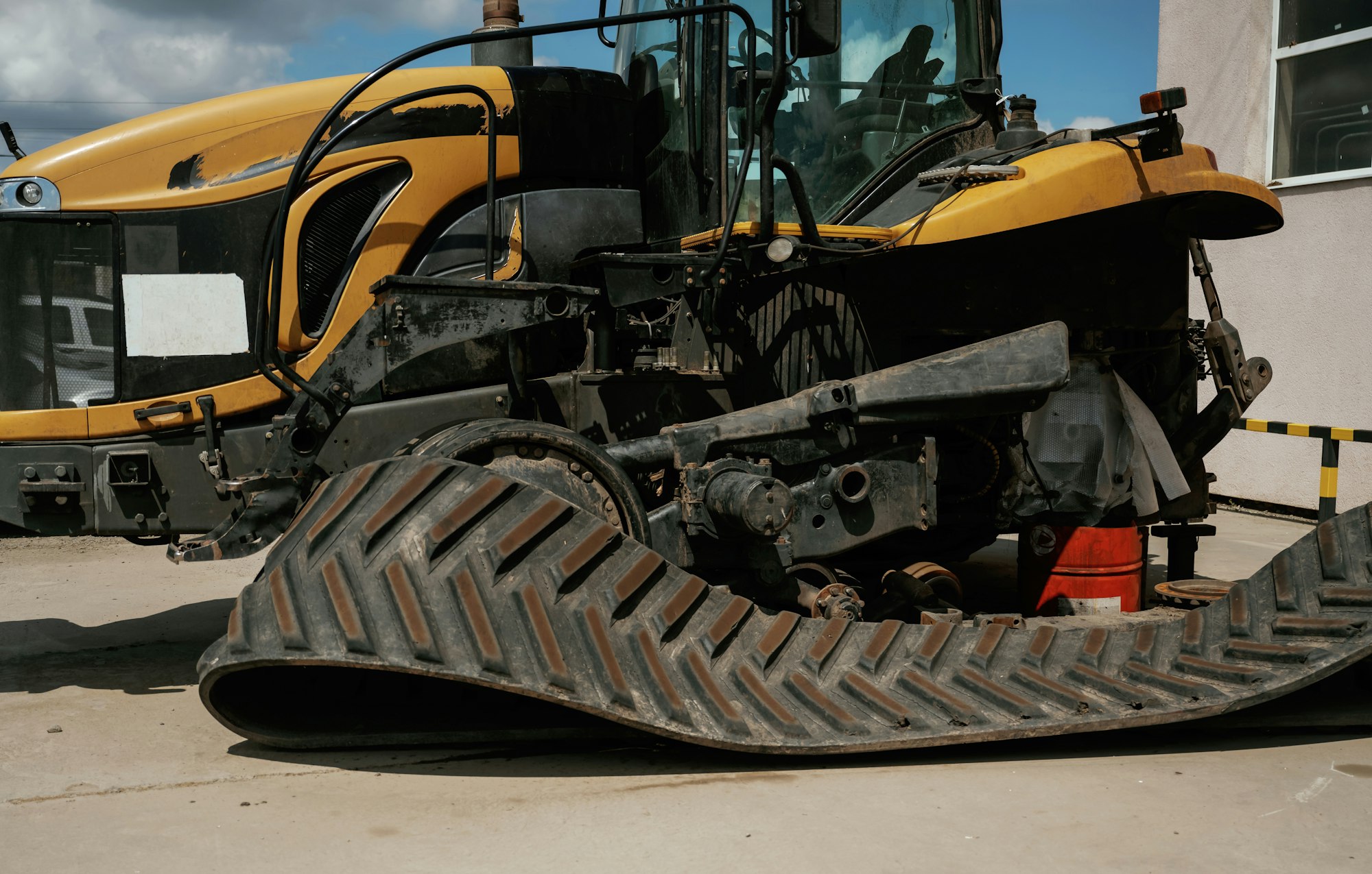 Industrial yellow bulldozer with damaged rubber track in repair yard